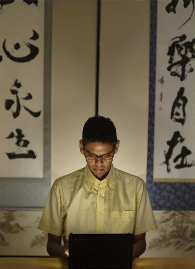 Dave working at his laptop in front of Japanese calligraphy scrolls